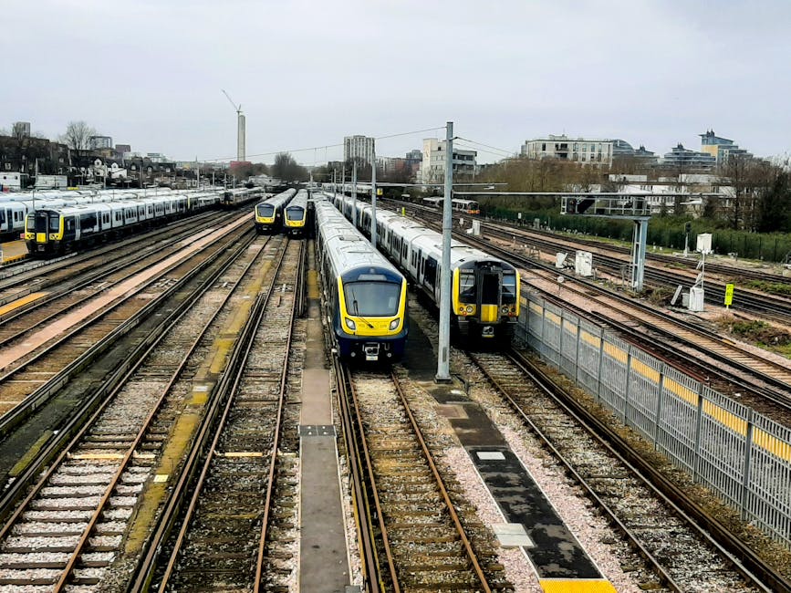 A series of modern commuter trains with yellow and grey livery are stationary on railway tracks near Richmond Station, with multiple parallel tracks and overhead electric wires visible in the scene. I